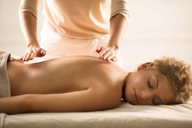 A topless woman was receiving back reiki therapy from the person next to her